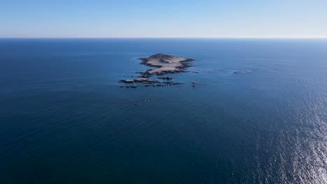 epic panoramic view of isolated tropical island with view of deep blue ocean water and horizon on sunny day