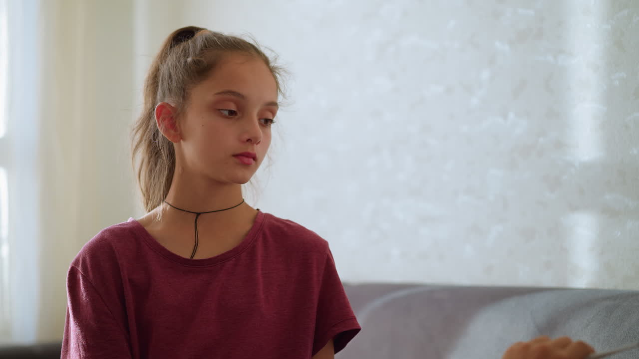 Worried girl holding thermometer, preparing to give it to someone lying down, concerned expression, soft sunlight highlighting the moment, indoor setting with a calm and caring atmosphere