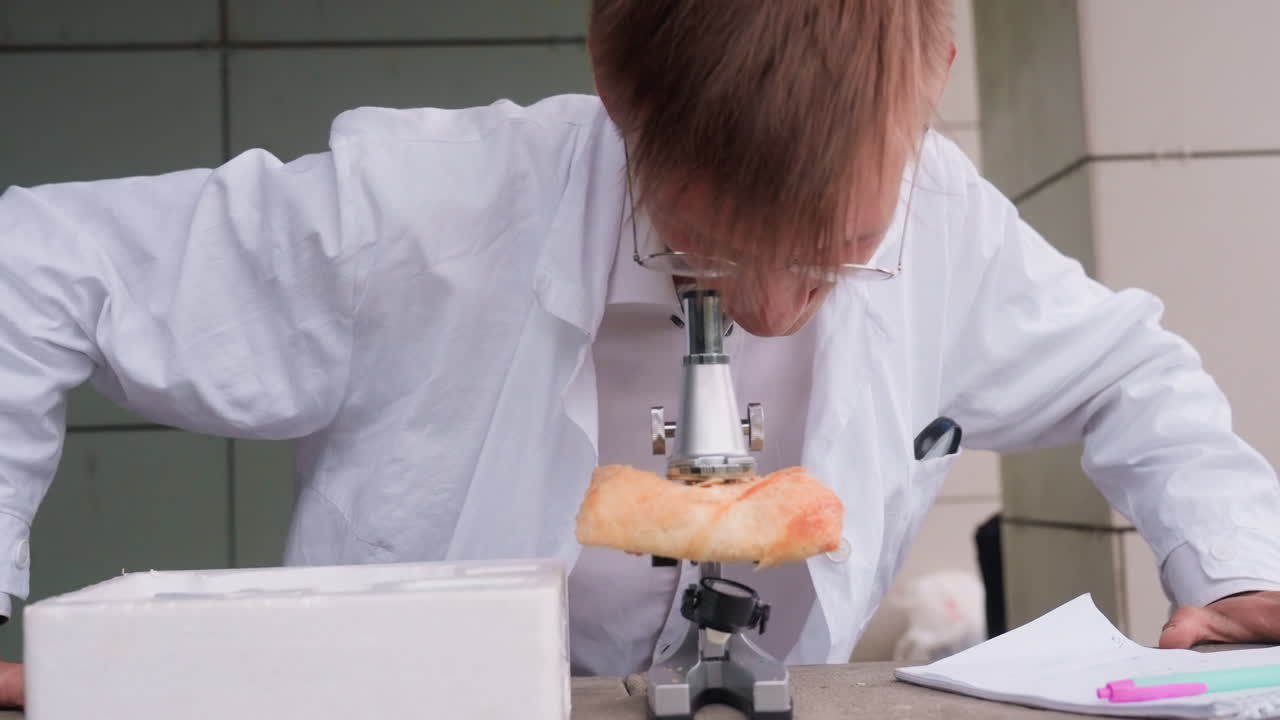 Close view of young ecologist in white coat carefully examining pastry closely through microscope in outdoor setting, reflecting curiosity, focus, dedication, and scientific observation