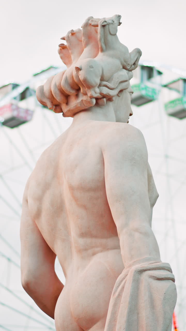 Nice, France - December 8, 2024: Apollo statue in the Fontaine du Soleil at Place Massena with a ferris wheel on the background. Vertical