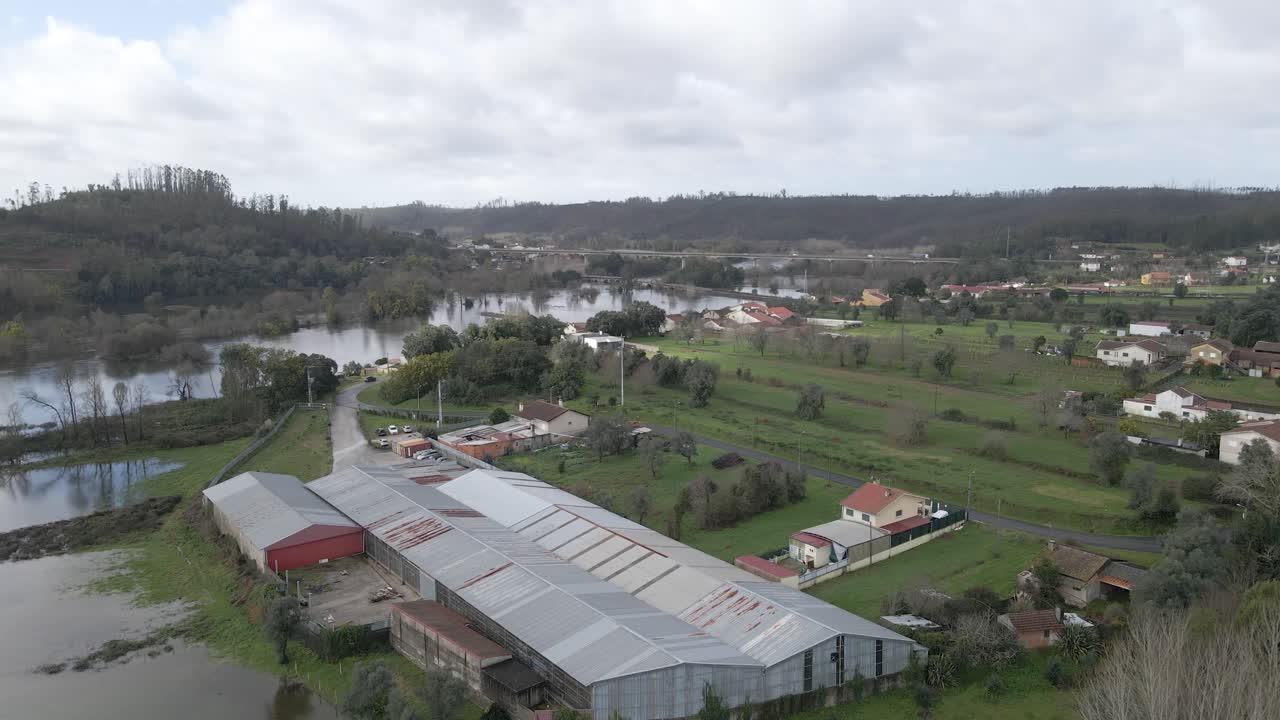 La vista aerea mostra estese inondazioni nelle aree pianeggianti di Aveiro, dove le forti piogge hanno trasformato i campi in ampi laghi temporanei. Un drone avanza sopra il fiume in direzione di una fattoria.