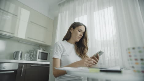 mujer usando teléfono móvil en la cocina. mujer usando teléfono celular en casa