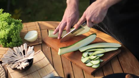 Hochwinkelaufnahme-Eines-Männchens,-Das-In-Seinem-Garten-Zucchini-In-Lange-Scheiben-Schneidet