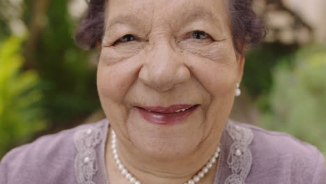 close up portrait of beautiful elderly woman looking smiling at camera wearing pearl necklace