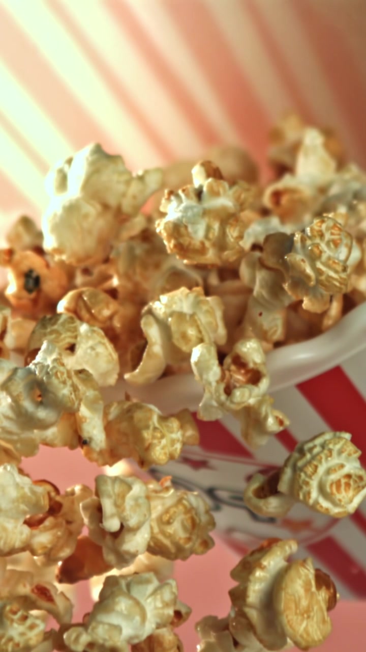 Popcorn au caramel sucré tombant dans une boîte rayée rouge et blanche