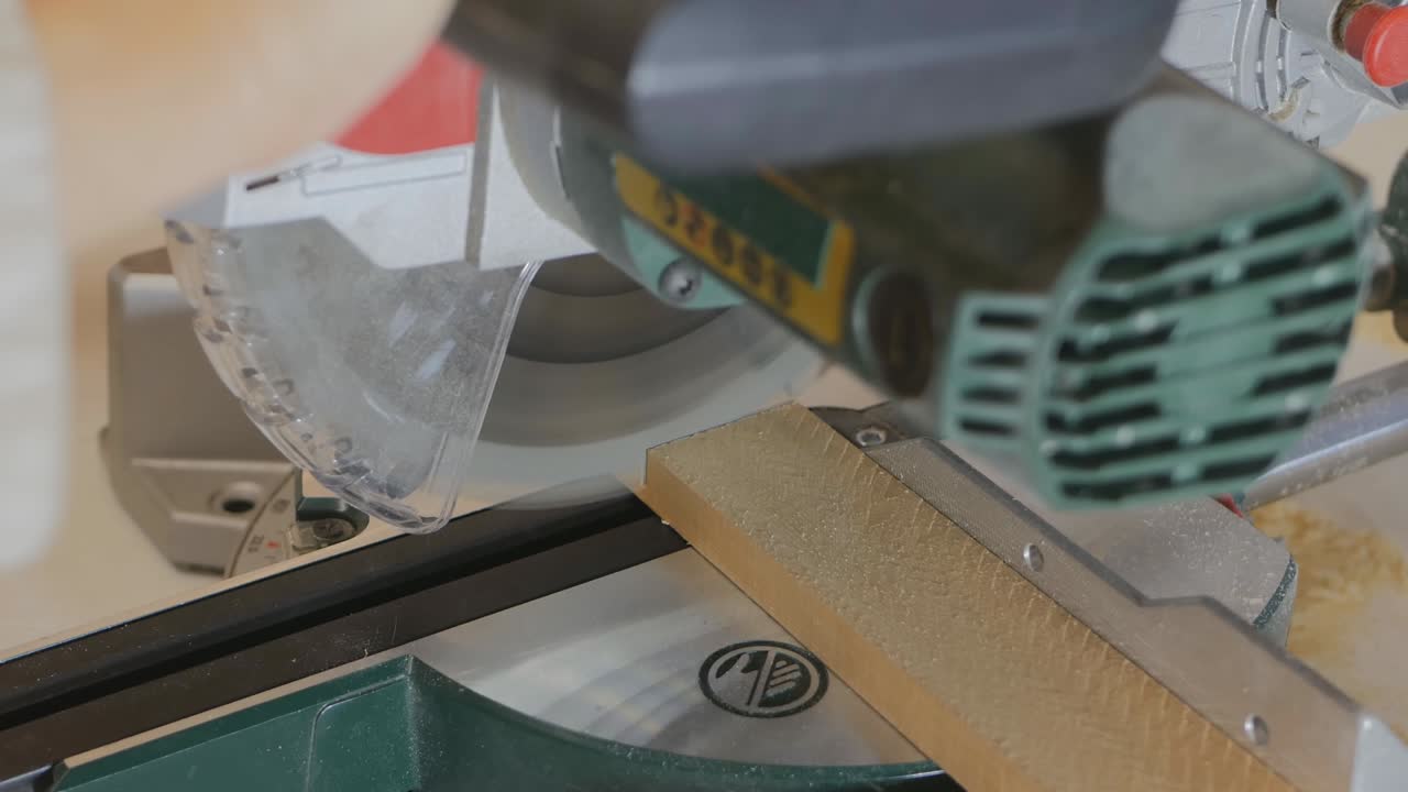 cortar productos de madera con una sierra de mitra. una mujer carpintero aserró una tabla en dos. trabajando con productos de madera en su taller. 4k