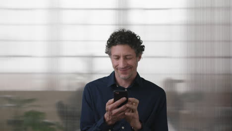 portrait-of-attractive-caucasian-man-texting-browsing-using-smartphone-enjoying-mobile-technology-in-office-background