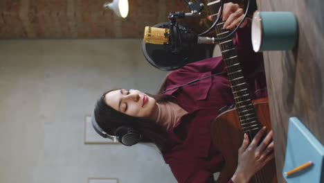 Female-Vlogger-Playing-Guitar-and-Speaking-on-Camera-in-Studio