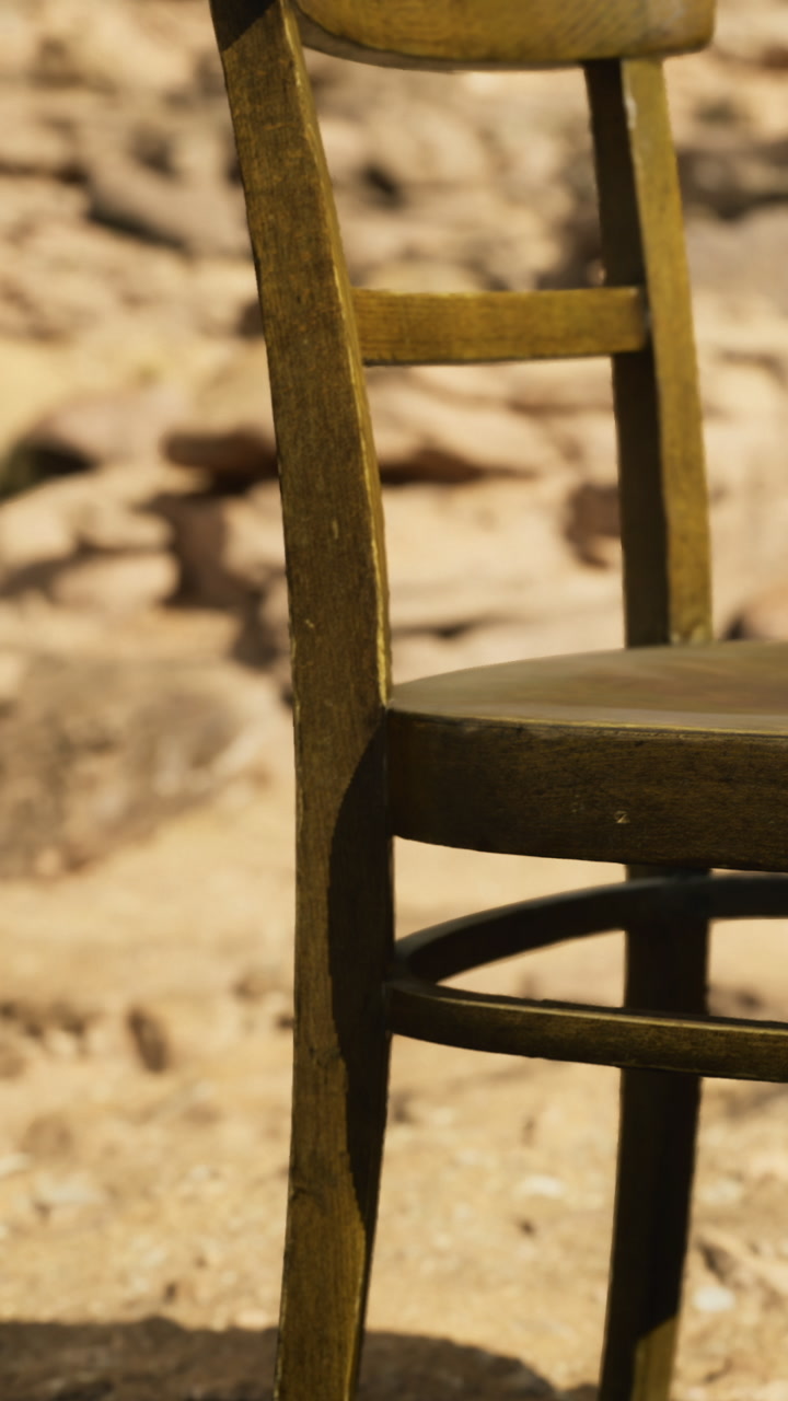 Old wooden chair sits alone in a sunlit desert landscape