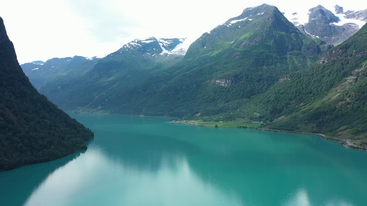 Ampia vista panoramica sulla splendida valle di Oldedalen con ghiacciai sulle cime delle montagne e lago di acqua dolce verde smeraldo - Ripresa aerea laterale nel mezzo del lago glaciale Olden - Norvegia
