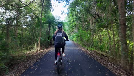 a person cycling through a lush green forest path