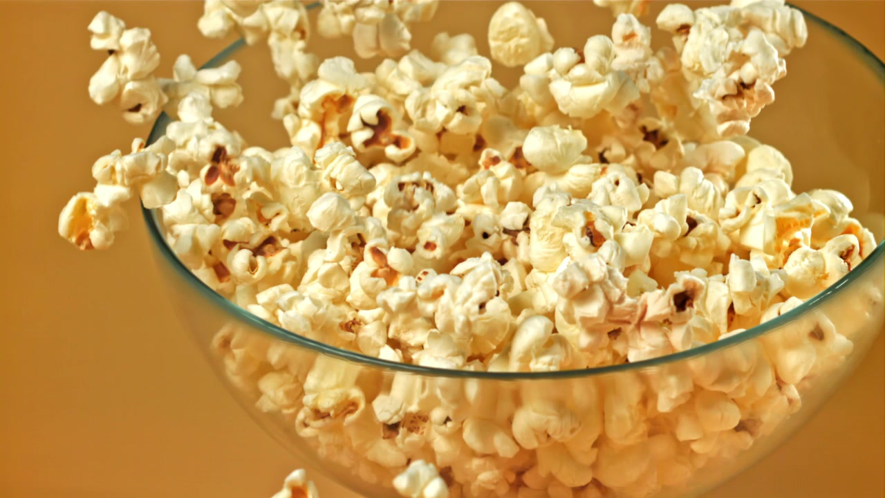 Popcorn freschi che riempiono e traboccano da una ciotola di vetro trasparente