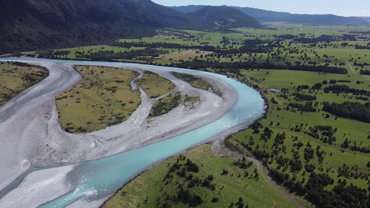 vista de avión no tripulado del río azul con agua de glaciar que fluye entre los campos en la costa oeste, nueva zelanda