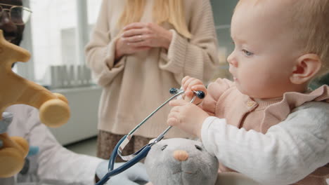 baby playing with pediatrician while visiting clinic with mom