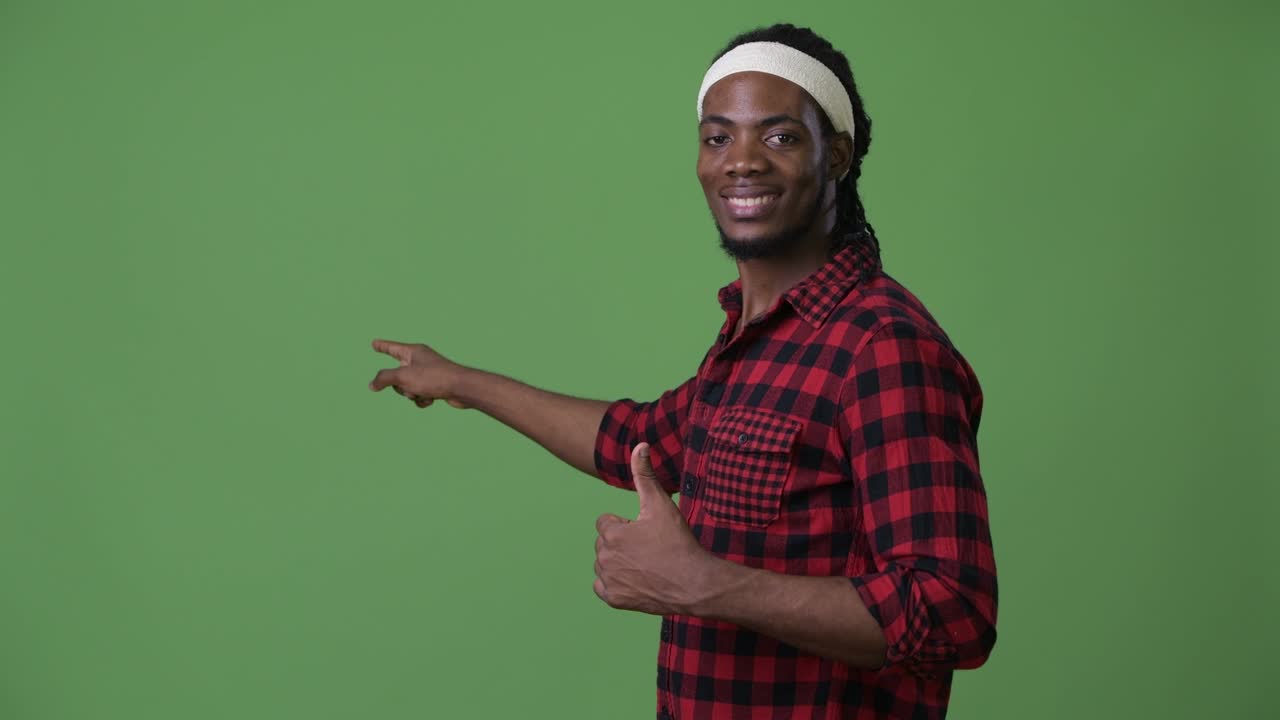 joven hombre africano guapo con dreadlocks contra un fondo verde