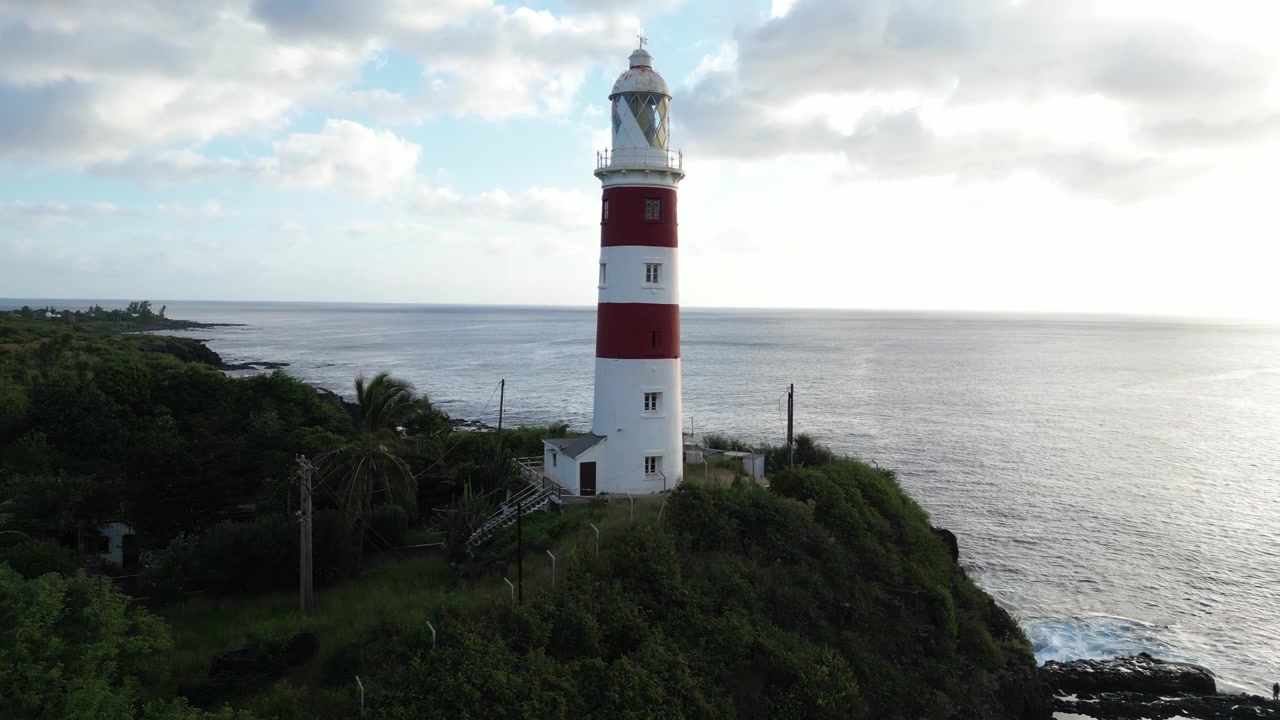 Vista aerea con drone dello storico faro di Albion rosso e bianco che si erge su una scogliera rocciosa verde a picco sull'oceano a Mauritius. Architettura costiera iconica di un'isola tropicale