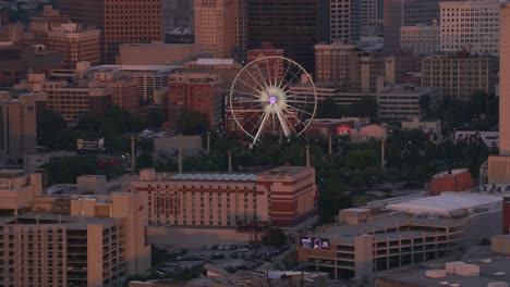 aerial shot of ferris wheel in downtown atlanta at sunset.