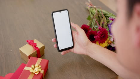 hombre biracial con regalos haciendo una llamada de video en el teléfono inteligente con espacio de copia en la pantalla, cámara lenta