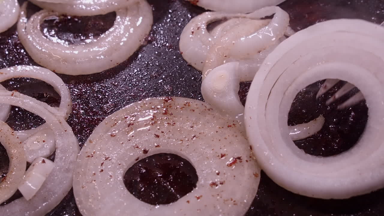 신선한 생 양파 반지는 스토브 위의 뜨거운 기름 비에 뿌려집니다.