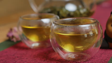 two cups of tea and a glass tea pot on a table.