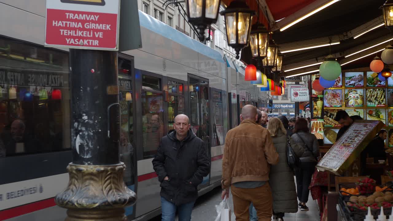 люди проходят мимо киоска с едой на улице в стамбуле, турция, на заднем плане - трамвай.
