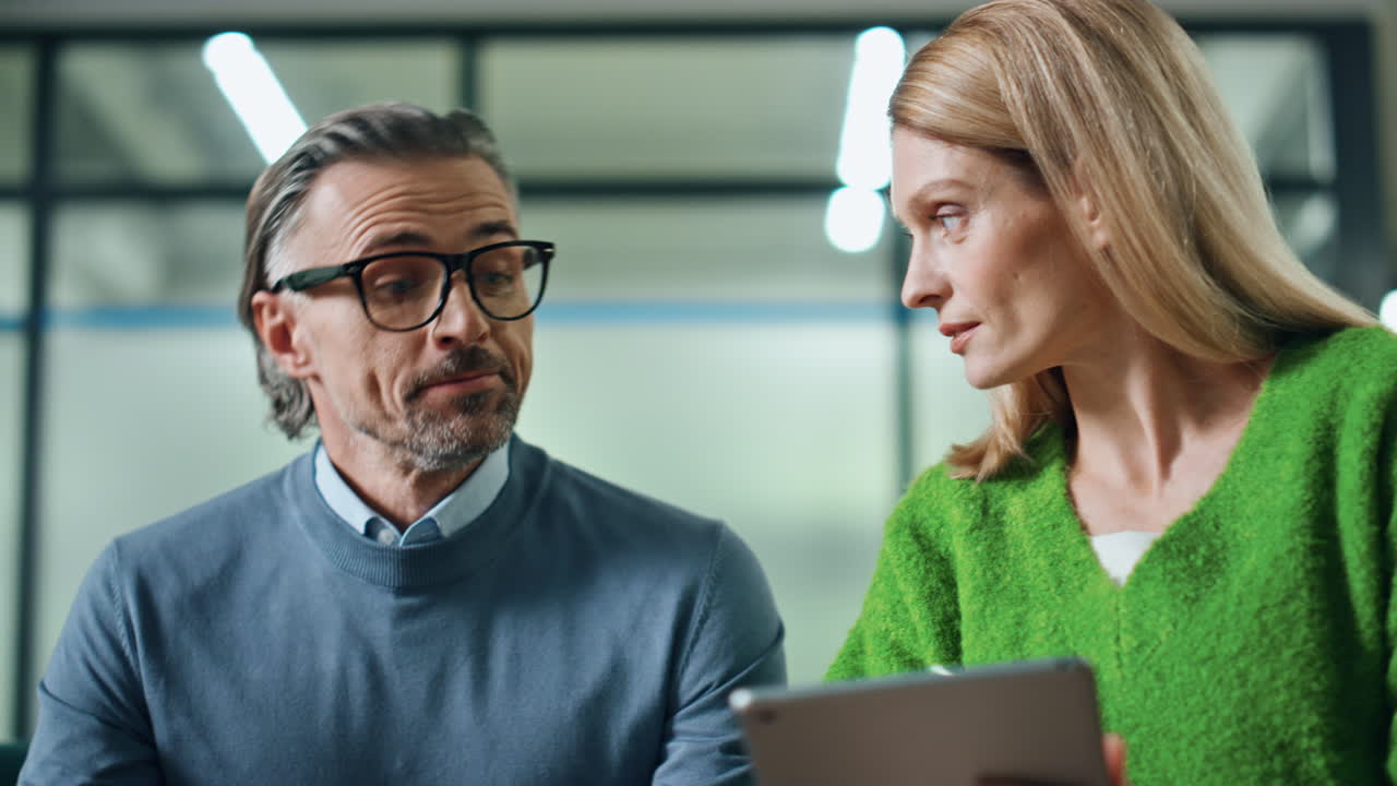 사무실에서 함께 일하는 매니저 커플. 태블릿을 논의하는 동료