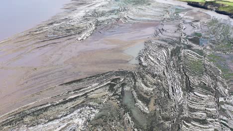 Drone-shot-while-tilting-up-over-Kilve-beach-and-its-sea-cliffs-in-North-Devon,-UK