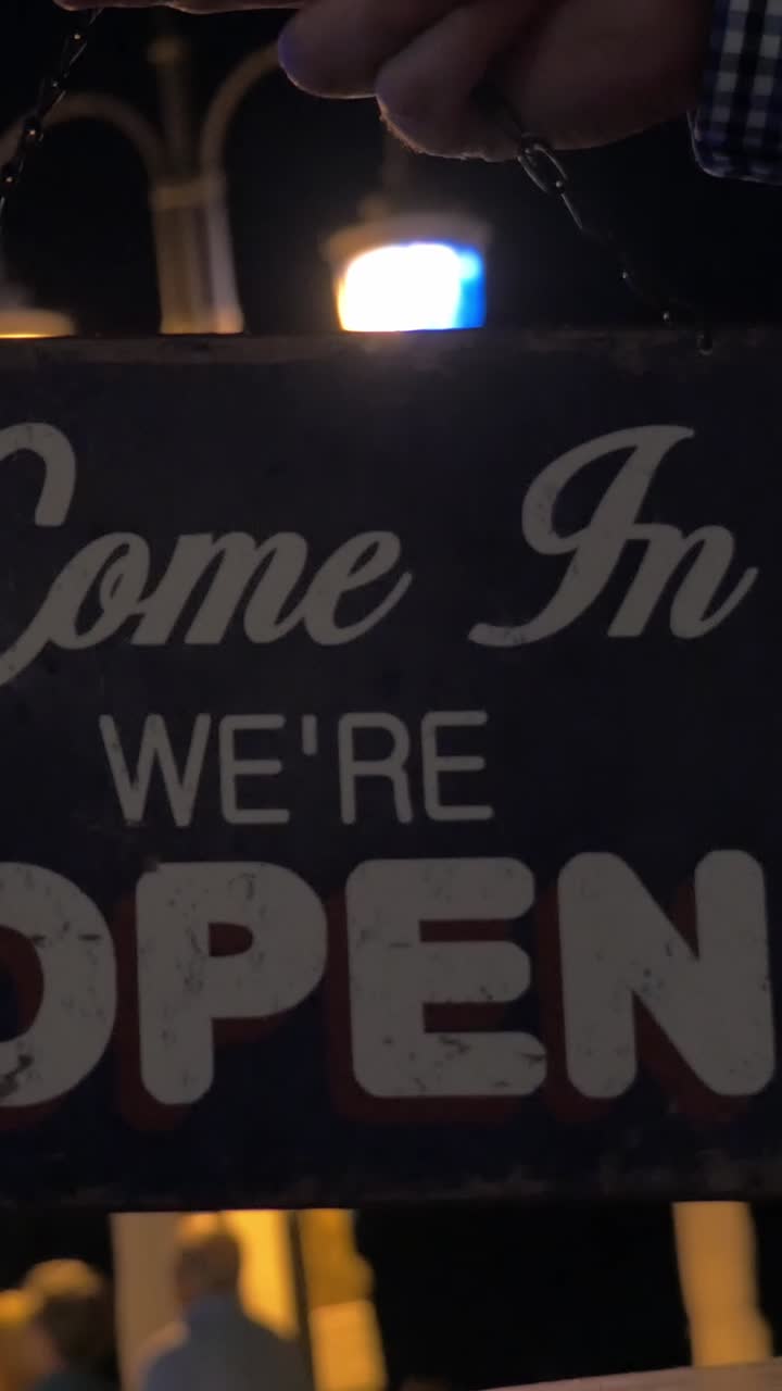 Hand Flipping a 'Closed' Sign to 'Open' at Night