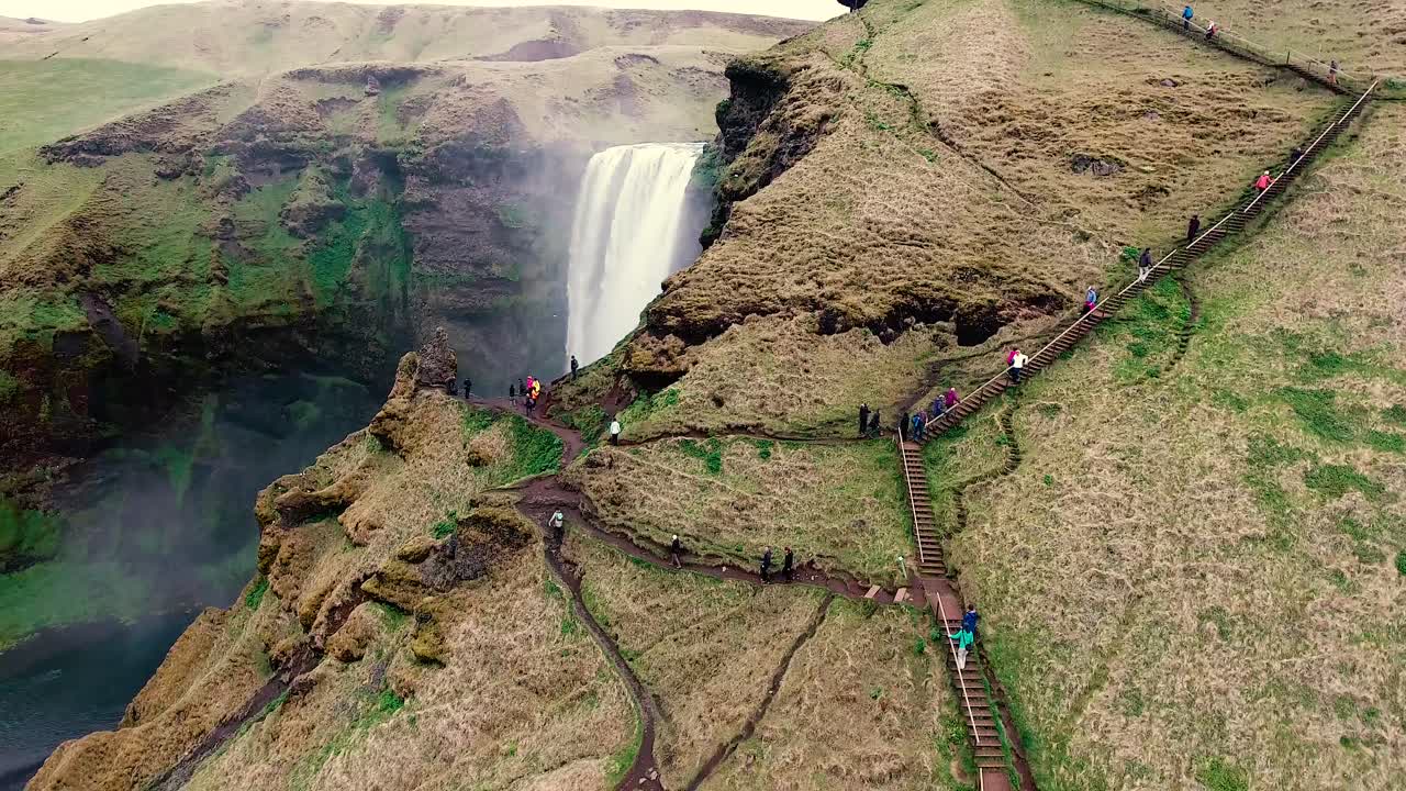 Seljalandsfoss Waterfall in Iceland, a bottom to top view with camera gimbal rotation view the climbers and hikers up a path to the top view point of the glacier fed waterfall. DJI phantom drone 4K