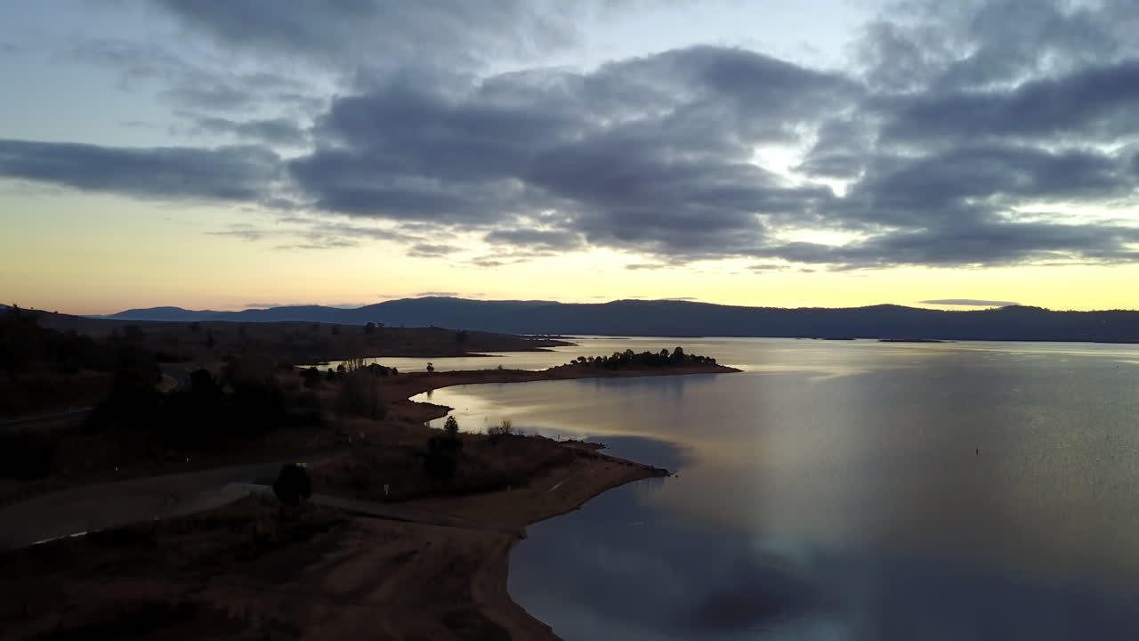 reflexión escénica del paisaje nublado en el lago tranquilo en jindabyne, nueva gales del sur, australia durante la puesta de sol