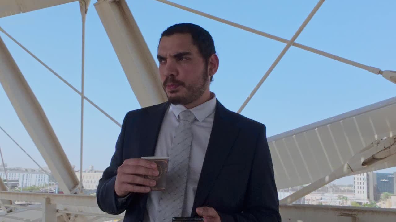 Dirigente determinato con caffè e telefono su un ponte all'aperto