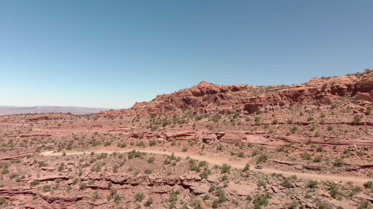 Un SUV argento percorre una strada sterrata rossa in una zona aspra di canyon, Moab, Utah.