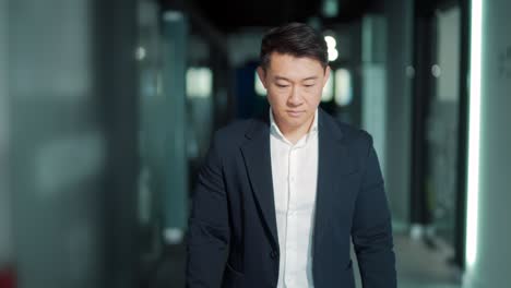 portrait of a successful confident asian male office worker standing and looking at the camera in a formal suit indoors. the face of a business man or entrepreneur employee