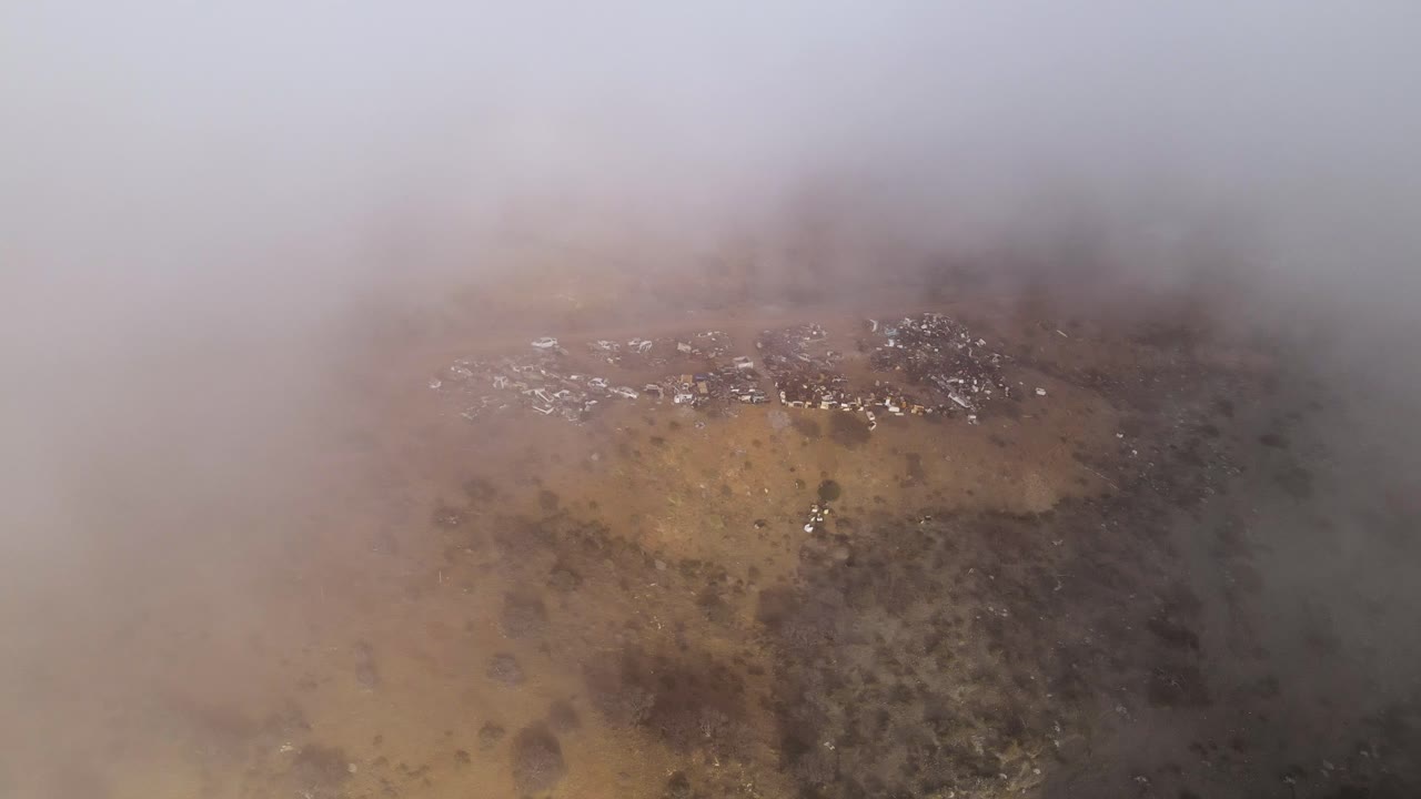 Dense mist covering Cedros Island’s coastline, dramatic and moody weather scene in the early morning, aerial flythrough reveals town in hillside