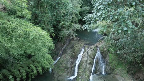 vista de dron descendente de una chica tomándose un selfie frente a una cascada