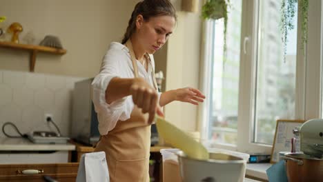 woman baker prepares flour in a kitchen