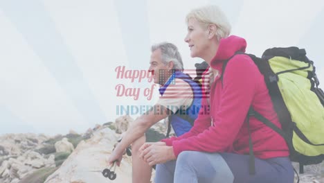 animation of independence day text over smiling senior caucasian couple sitting on rocks