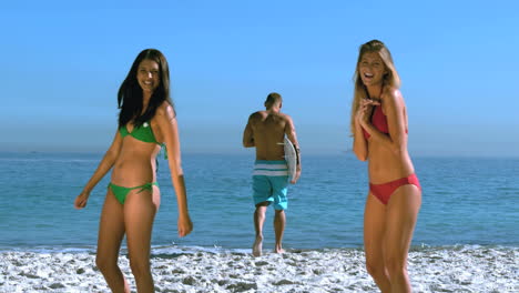 chicas bonitas admirando a un amigo corriendo hacia el mar
