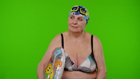 Elderly-woman-tourist-in-swimsuit-bra,-swim-goggles-with-swimming-ring,-looking-around-on-chroma-key