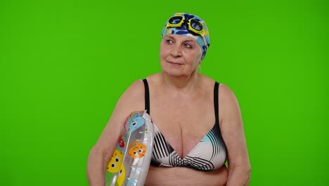 turista de edad avanzada en sostén de traje de baño, gafas de natación con anillo de natación, mirando a su alrededor en la llave de croma