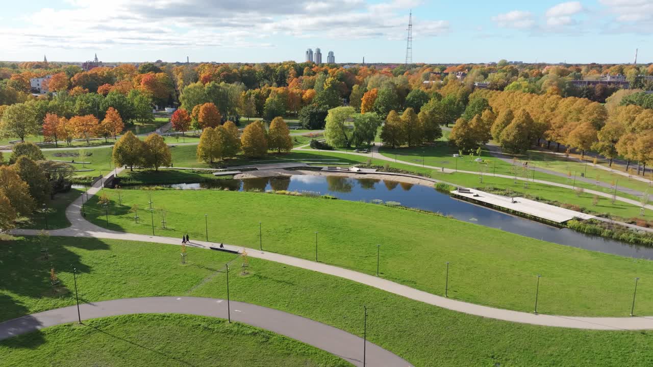 Drone Captures Victory Park in Riga, Two People Walking Along Curved Pathway