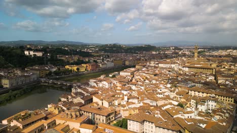 sunlight streams down on ancient city of florence italy with cloud shadow over canal and mountain