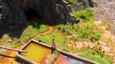 aerial of a girl in a long dress walking on concrete water reservoir near abandoned mine in madzharovo