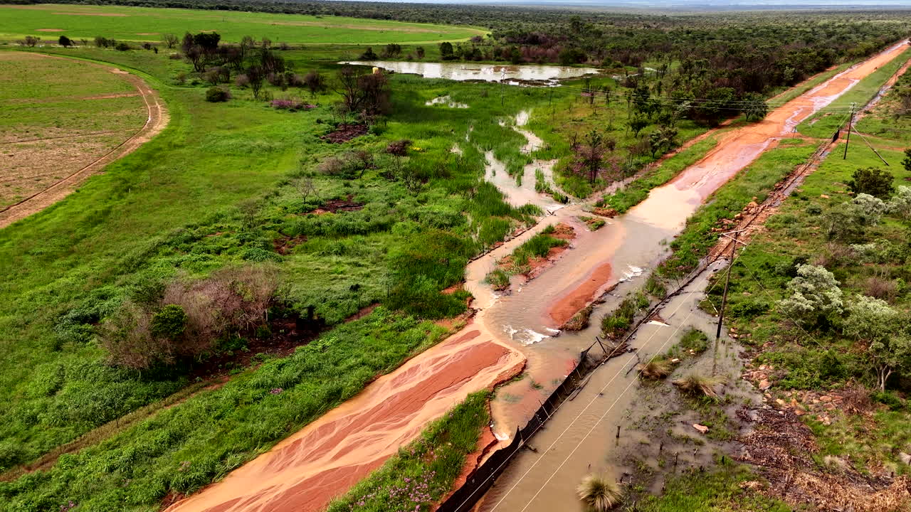 Flooded sand road, damaged after heavy rain in Africa, showcasing large water pools and mud