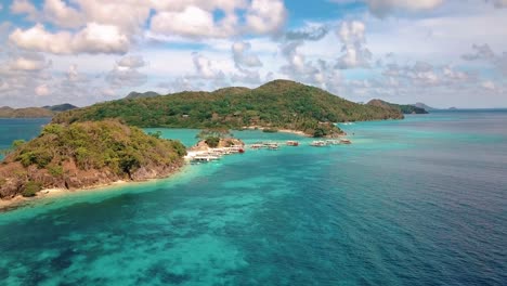 Aerial-shot-of-Bulog-Island-in-Coron,-Palawan,-Philippines-with-tourists-swimming-and-boats-parked-by-the-beach