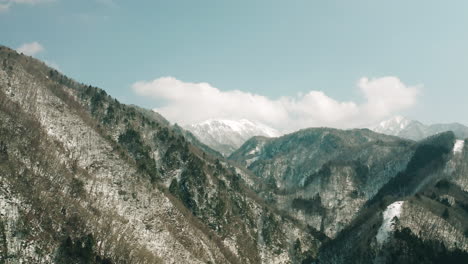 drone footage of snow-covered mountains during daytime in okuhida, japan