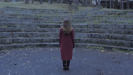 woman in red coat standing in an outdoor amphitheater