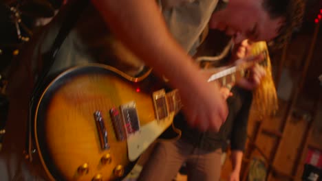 Closeup-of-a-man-playing-bass-as-a-woman-with-a-microphone-dances-in-the-background