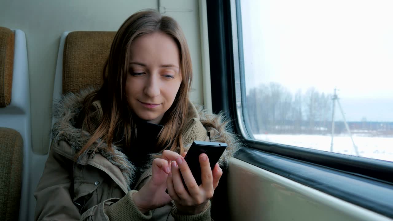 mujer pensativa viajando en un tren y usando un teléfono inteligente