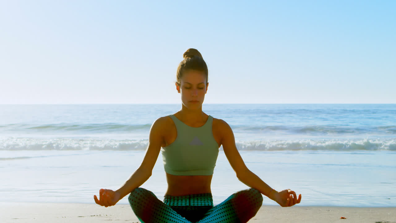 mujer en forma realizando yoga en la playa 4k
